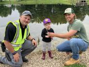 Officer Tyler Barr helps a child bring in a small fish they caught at the Cops and Bobbers Event.