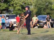 Photo of a crowd watching a Police Officer Shawn Deneen and his K9 partner Teddy perform a public demonstration.